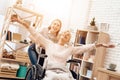 Girl is nursing elderly woman at home. Girl is riding woman in wheelchair. Woman feels like flying. Royalty Free Stock Photo