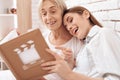 Girl is nursing elderly woman at home. They are watching photos in photo album. Royalty Free Stock Photo