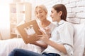 Girl is nursing elderly woman at home. They are watching photos in photo album. Royalty Free Stock Photo