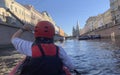 A girl with an oar floats on a red kayak, view from the back. Morning boat trip