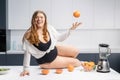 Girl with obese problem. Young sexy chubby white girl in black swimsuit, white shirt at modern kitchen table. juggling