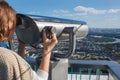 Girl on the observation deck , moscow city panorama. Woman looks binoculars at the city on the observation deck
