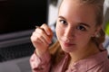 Girl in office sits in front laptop and holds pen