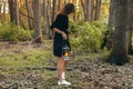 Girl with oil lamp is walking at the wilderness and looking for. Dark forest, evening. Summer time. Travel story