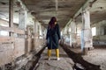 A girl in an old abandoned scary room like a barn or stable. An abandoned factory barn and stable where cows and horses lived. Royalty Free Stock Photo