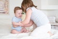 Girl older sister hugging her little baby boy brother on bed at home Royalty Free Stock Photo