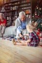 Girl is open Christmas present in front of a decorated X-mas tree with grandpa Royalty Free Stock Photo