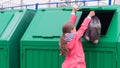 The girl opened the dumpster to vibrate the waste bag