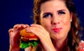 Girl opened her mouth, holding a hamburger on his outstretched hands and closed her eyes.