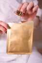 The girl opens a fabric face mask. beauty procedures. Close-up of a hand holding a gold-colored mask. A sheet mask for a pampering