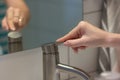The girl opens the faucet for washing hands, in the mirror reflected her hand