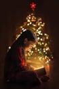 A girl opens a gift from Santa Claus on Christmas night. Royalty Free Stock Photo