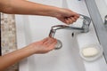 The girl opens the handle of the mixer in order to wash her hands