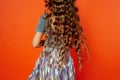 Girl on orange background in the Studio. Very long curly hair like in a fairy tale.Rapunzel. developing in the movement