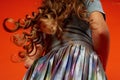 Girl on orange background in the Studio. Very long curly hair like in a fairy tale.Rapunzel. developing in the movement