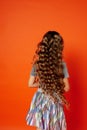 Girl on orange background in the Studio. Very long curly hair like in a fairy tale.Rapunzel