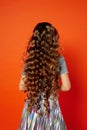 Girl on orange background in the Studio. Very long curly hair like in a fairy tale.Rapunzel