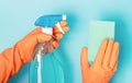 A girl in orange gloves holds a spray bottle and sponge against blue background Royalty Free Stock Photo