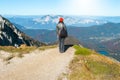 Girl with orange hat and black bag standing on an edge of a cliff on a nice autumn sunny day trip in Julian alps trekking high in