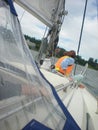 A girl in an orange rescued vest sits on the bow of a sailing yacht in windy and rainy weather, in bad weather, the horizon is Royalty Free Stock Photo