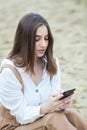 Girl outdoors texting on her mobile phone. Girl with phone. Portrait of a happy woman text sms message on her phone. Royalty Free Stock Photo