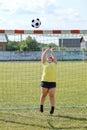 Girl with overweight stands in football gate and jumps to catch ball with his hands