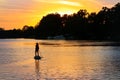 Girl paddling on SUP board on beautiful lake during sunset or sunrise, standing up paddle boarding morning adventure in Germany Royalty Free Stock Photo