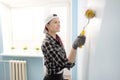 Girl painter, designer and worker paints a roller and brush the wall. Smiling, working with pleasure, close-up. Royalty Free Stock Photo