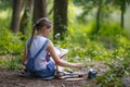 Girl painter paints trees in the park.