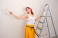 The girl painter in Russian or Ukrainian style stands in the headscarf next to the ladder Royalty Free Stock Photo