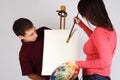 Girl painting on canvas easel, man looking