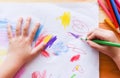 Girl painting on paper sheet with colour pencils on the wooden table at home - child kid doing drawing picture and colorful crayon Royalty Free Stock Photo