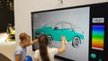 A girl paints a car on an interactive whiteboard