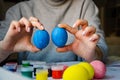 Girl paints an egg blue for the holiday at Easter. girl draws with a brush on a chicken egg Royalty Free Stock Photo