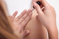 Girl paints nails . a woman in a man`s shirt . sitting on . floor. care of yourself .