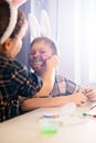 The girl paints the rabbit ears face of the boy in the headband with paint using a brush. Easter Celebration