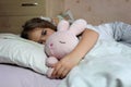 Girl in pajama sleeping and hugging her toy hare