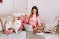 A girl in pajamas at home is working on a laptop with her dog Spitzer, the dog and its owner are resting on the couch and watching Royalty Free Stock Photo