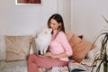 A girl in pajamas at home is working on a laptop with her dog Spitzer, the dog and its owner are resting on the couch and watching Royalty Free Stock Photo