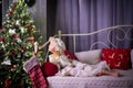 A girl in pajamas lies on a bed next to a Christmas tree