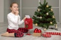 girl in pajamas near the Christmas tree throws a letter to Santa in the mailbox, Christmas gifts Royalty Free Stock Photo