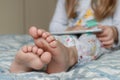 Girl in pajamas sitting barefoot on the bed and playing on the tablet Royalty Free Stock Photo