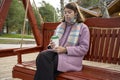 girl with paper cup of coffee swings on bench in the park Royalty Free Stock Photo