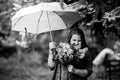 A girl in the park with a bouquet under an umbrella. Black and white photo.