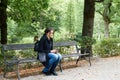 A girl in the park sits alone on a bench with a phone Royalty Free Stock Photo