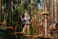 A girl passes an obstacle in a rope town. A girl in a forest rope park