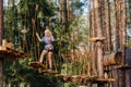 A girl passes an obstacle in a rope town. A girl in a forest rope park