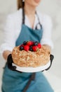 girl pastry chef holding honey cake with berries