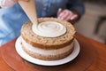 Girl Pastry Chef, makes a wedding cake with his own hands and squeezes the cream on the cake layers. Copy space. Selective focus. Royalty Free Stock Photo