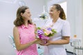 Girl patient gives a bouquet of flowers to a female doctor in dental office. National dentist`s day